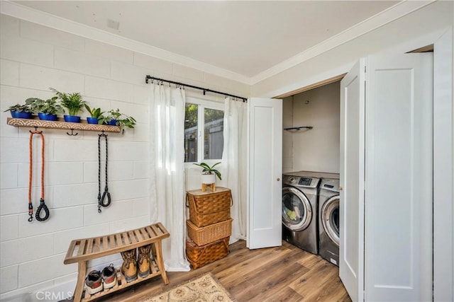 clothes washing area with light hardwood / wood-style floors, separate washer and dryer, and ornamental molding