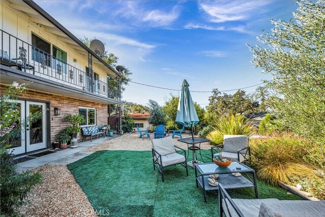 view of yard with a patio, french doors, and a balcony