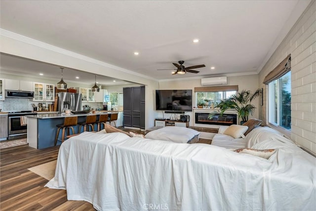 living room featuring ceiling fan, ornamental molding, a wall unit AC, and dark wood-type flooring