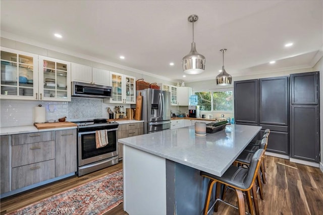 kitchen featuring white cabinetry, appliances with stainless steel finishes, hanging light fixtures, and a large island