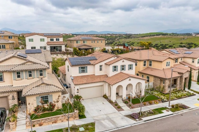 drone / aerial view with solar panels, a mountain view, and a garage