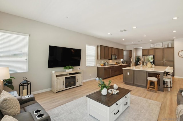 living room featuring sink, light wood-type flooring, and plenty of natural light