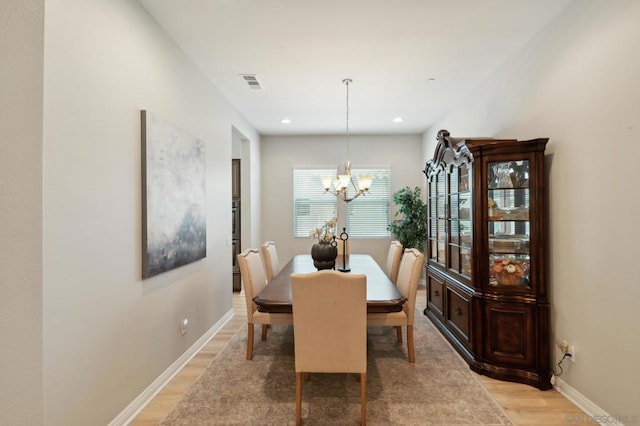 dining room with light hardwood / wood-style floors and an inviting chandelier