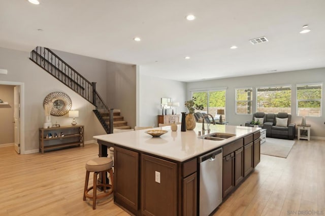 kitchen featuring dark brown cabinets, an island with sink, light wood-type flooring, dishwasher, and sink