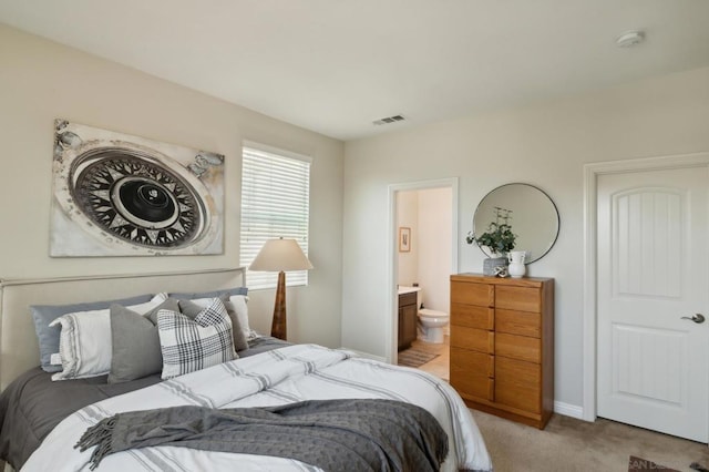 bedroom with ensuite bath and light colored carpet