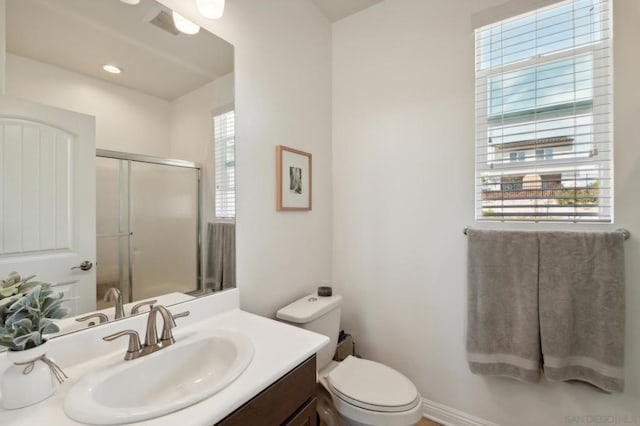 bathroom featuring toilet, a shower with shower door, and vanity