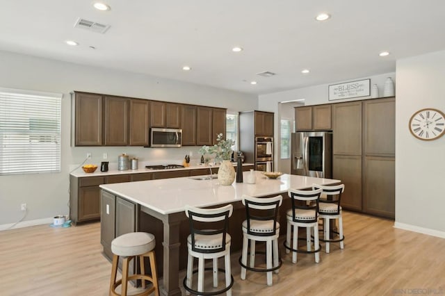 kitchen featuring light hardwood / wood-style floors, stainless steel appliances, and an island with sink