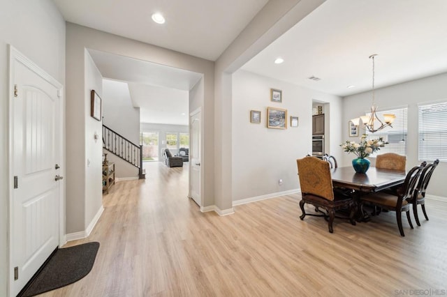 dining area with light hardwood / wood-style floors and a notable chandelier