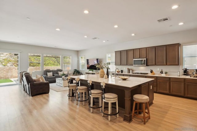 kitchen featuring stainless steel appliances, light hardwood / wood-style flooring, a center island with sink, and a kitchen breakfast bar