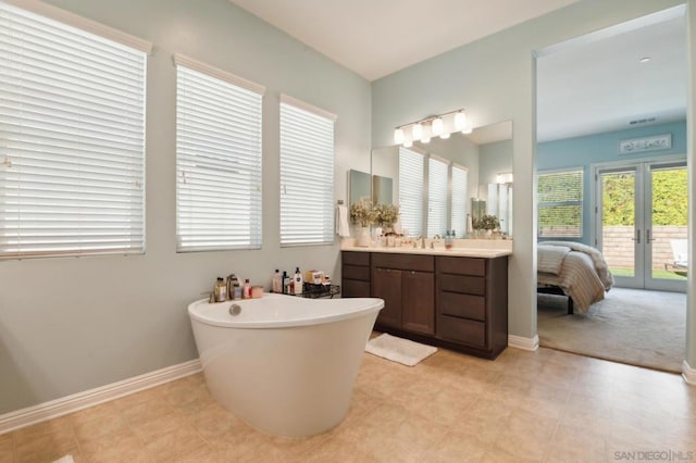 bathroom featuring vanity, french doors, and a bathing tub