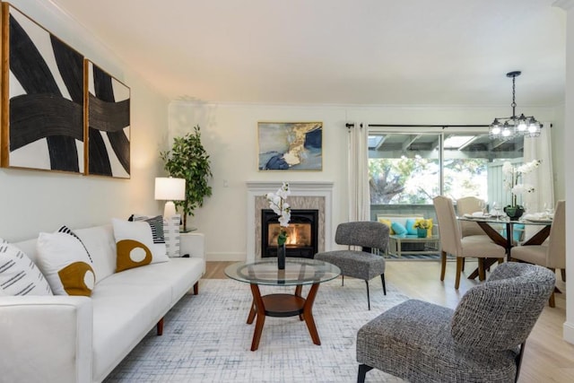 living room with hardwood / wood-style flooring, ornamental molding, a fireplace, and a notable chandelier