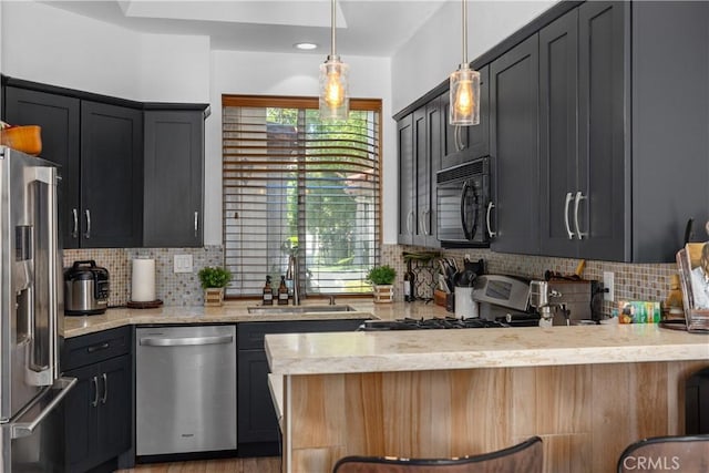 kitchen with pendant lighting, decorative backsplash, sink, and stainless steel appliances