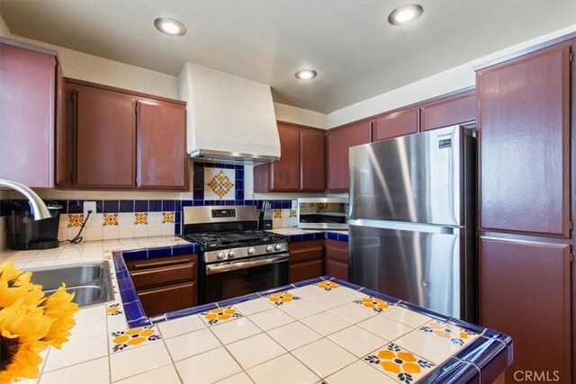 kitchen with sink, stainless steel appliances, tile countertops, decorative backsplash, and custom exhaust hood