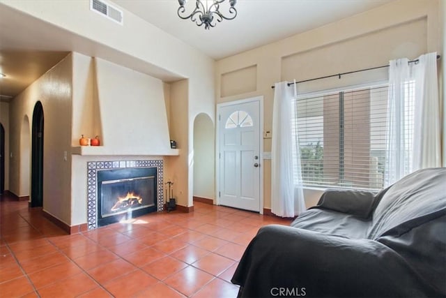 living room featuring a tile fireplace, tile patterned flooring, and an inviting chandelier