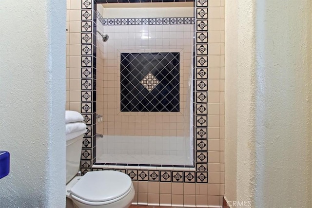 bathroom with toilet and tiled shower