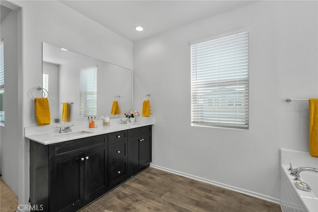 bathroom featuring vanity, wood-type flooring, and a tub to relax in