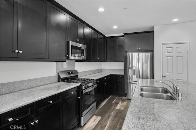 kitchen with light stone counters, sink, appliances with stainless steel finishes, and dark wood-type flooring