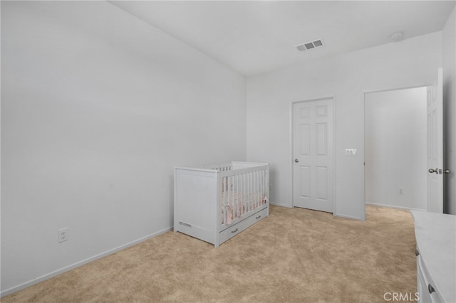 unfurnished bedroom with a crib and light carpet