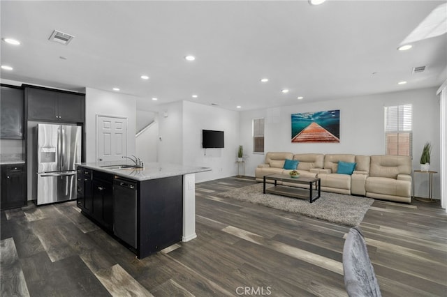 kitchen featuring dishwasher, a kitchen island with sink, sink, dark hardwood / wood-style floors, and stainless steel fridge