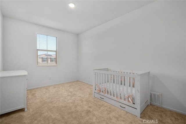 unfurnished bedroom with light colored carpet and a nursery area