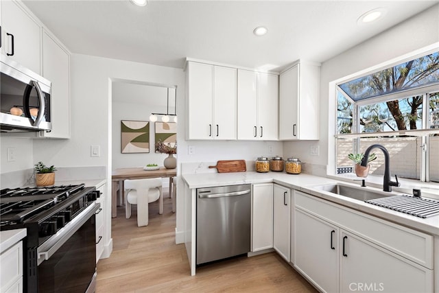 kitchen featuring sink, white cabinetry, light hardwood / wood-style flooring, and appliances with stainless steel finishes