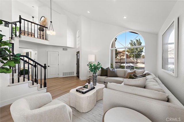 living room with high vaulted ceiling and light wood-type flooring