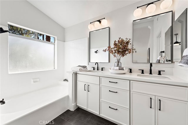 bathroom with a washtub, tile patterned floors, lofted ceiling, and vanity