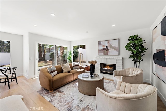 living room featuring a brick fireplace and light hardwood / wood-style flooring