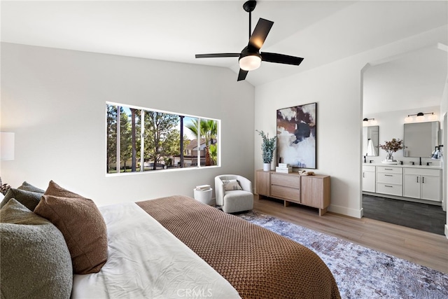 bedroom with connected bathroom, vaulted ceiling, ceiling fan, hardwood / wood-style flooring, and sink