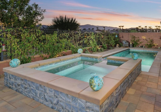 pool at dusk with an in ground hot tub