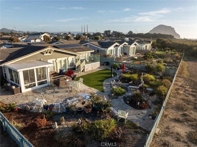 back of property featuring a patio area, a mountain view, a yard, and a sunroom