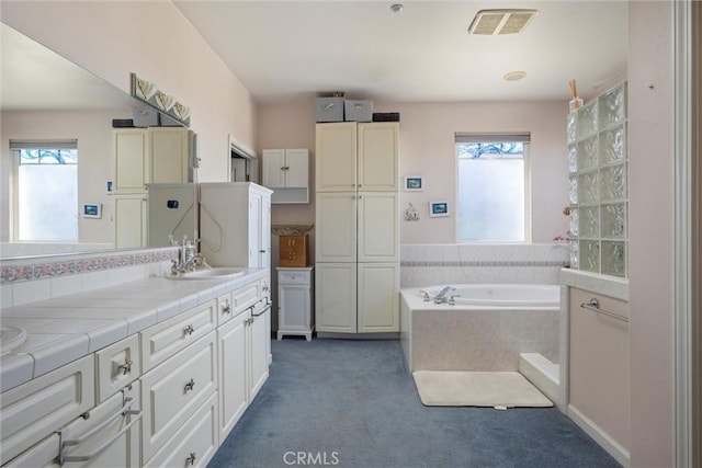 bathroom with vanity and tiled bath