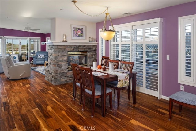 dining room featuring a wealth of natural light, a fireplace, and dark wood-type flooring