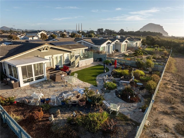 back of house with a lawn, a sunroom, a mountain view, and a patio