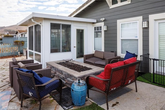 view of patio featuring a sunroom and an outdoor living space with a fire pit