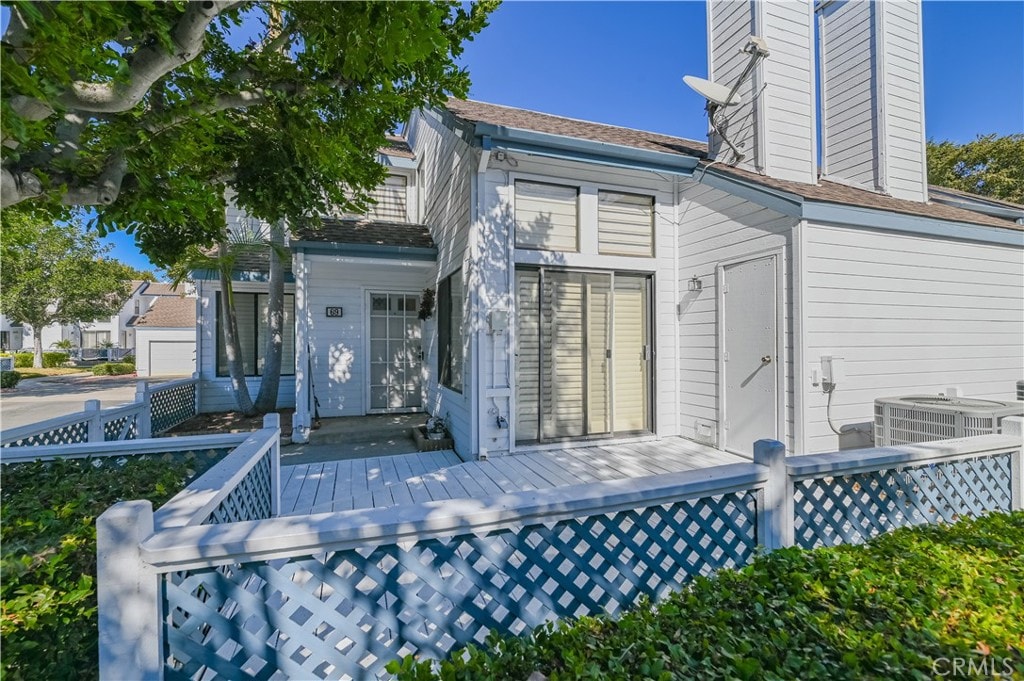 back of property with a garage, a deck, and central AC unit