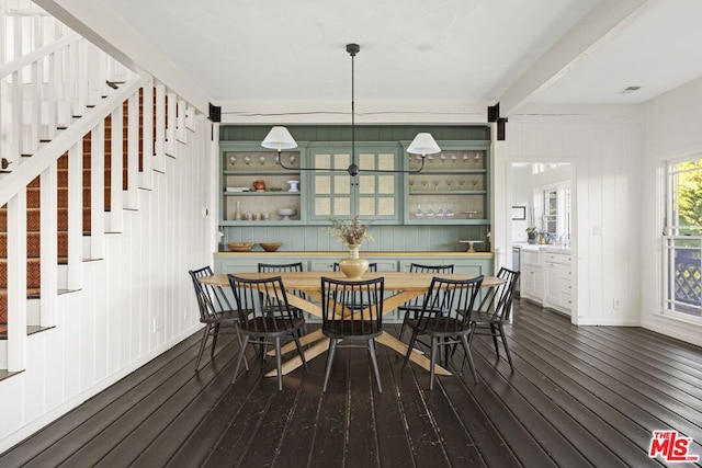 dining area with beam ceiling and dark wood-type flooring