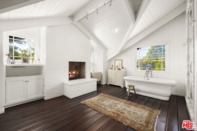 interior space with vaulted ceiling with beams, dark hardwood / wood-style floors, a wealth of natural light, and a brick fireplace