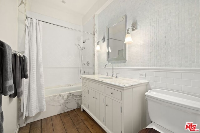 bathroom with hardwood / wood-style floors, vanity, shower / bath combination with curtain, and tile walls