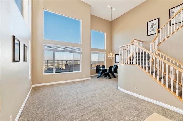 living room featuring carpet floors, a chandelier, and a high ceiling