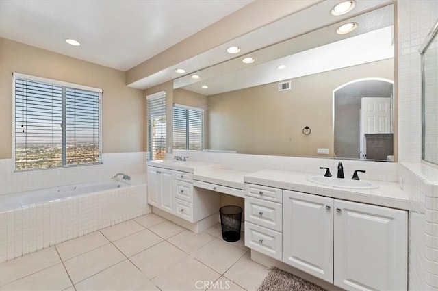 bathroom with tile patterned flooring, vanity, and tiled bath