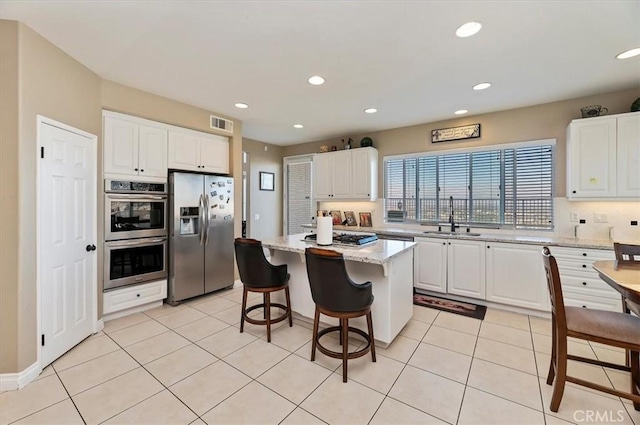 kitchen featuring white cabinets, appliances with stainless steel finishes, a kitchen island, and sink