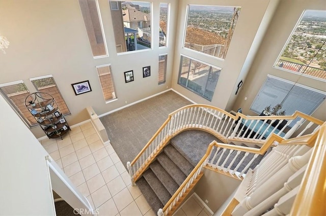 staircase featuring tile patterned floors and a towering ceiling