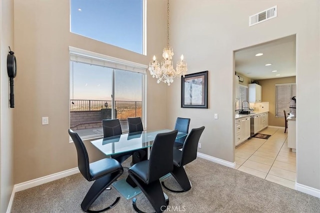 carpeted dining area with sink, a towering ceiling, and an inviting chandelier