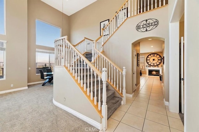 stairway with carpet and a towering ceiling