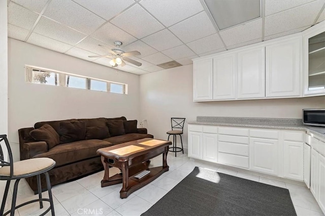 living room featuring a paneled ceiling, ceiling fan, and light tile patterned floors