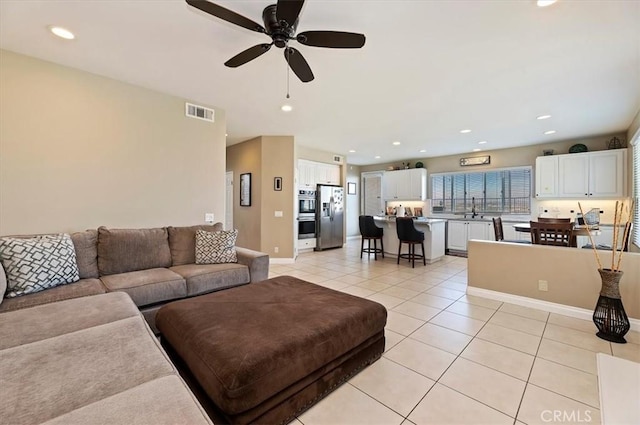 tiled living room with ceiling fan and sink