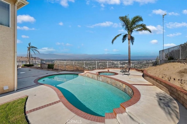 view of pool with an in ground hot tub, a mountain view, and a patio area