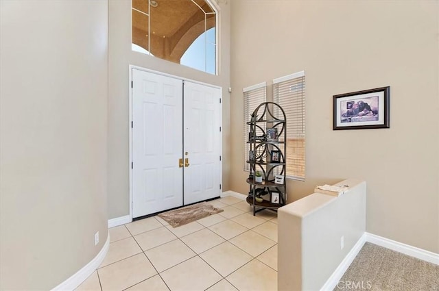 foyer entrance with a towering ceiling and light tile patterned flooring