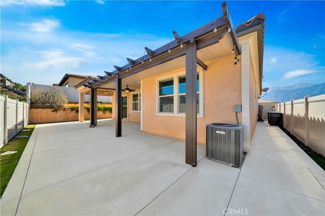 back of house featuring central AC unit, a mountain view, ceiling fan, and a patio area